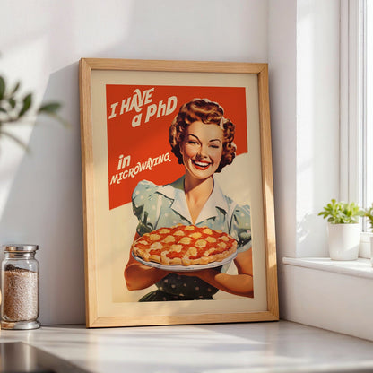 Retro housewife holding a pie with the quote “I Have a PhD in Microwaving,” vintage diner style funny kitchen wall art poster for mid century kitchen decor.