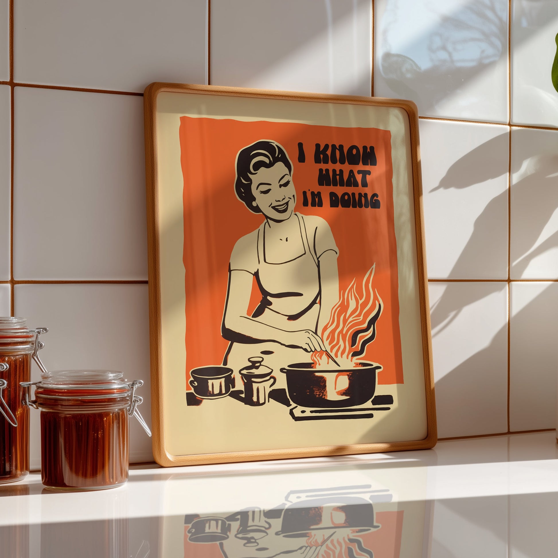 Midcentury housewife cooking over flames with the text “I Know What I’m Doing,” nostalgic retro kitchen wall art print for family kitchen decor.