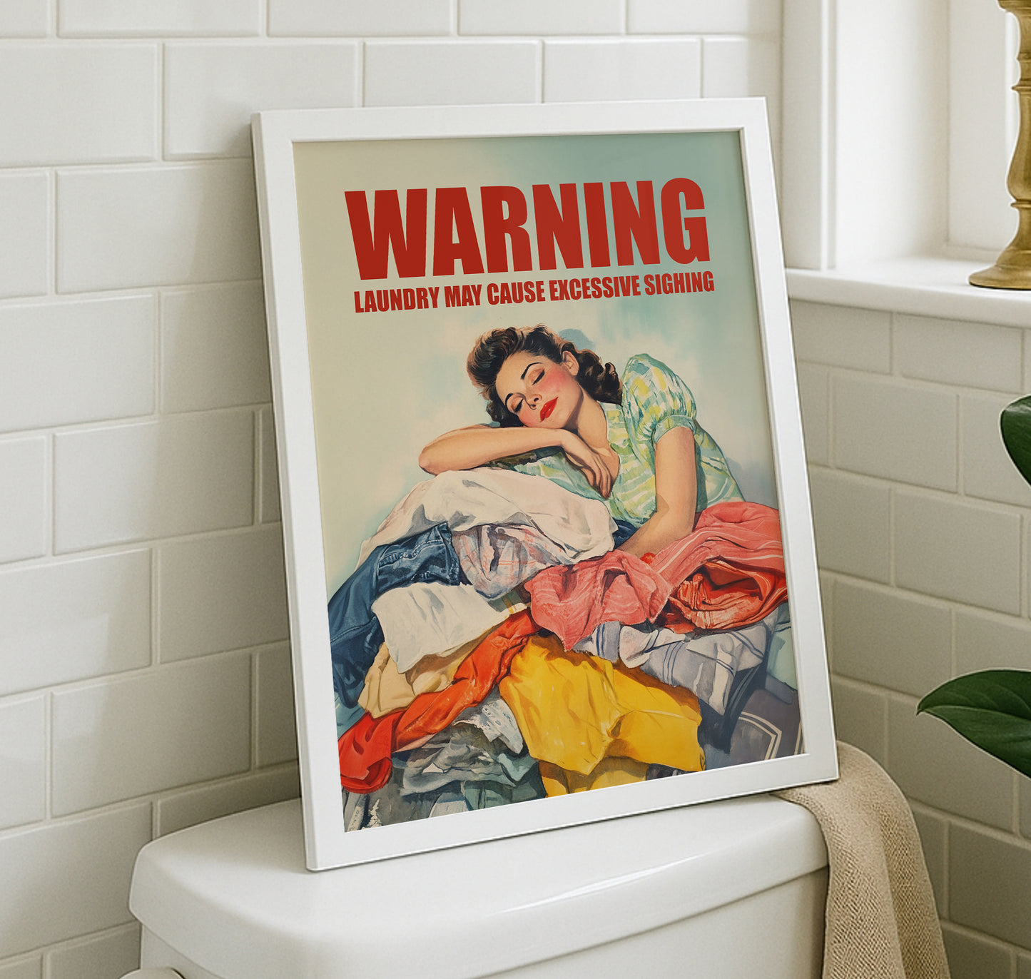 Vintage illustration of a 1950s housewife leaning her head on a large pile of colorful laundry with 'WARNING: LAUNDRY MAY CAUSE EXCESSIVE SIGHING' in bold red text; funny retro laundry room wall art.