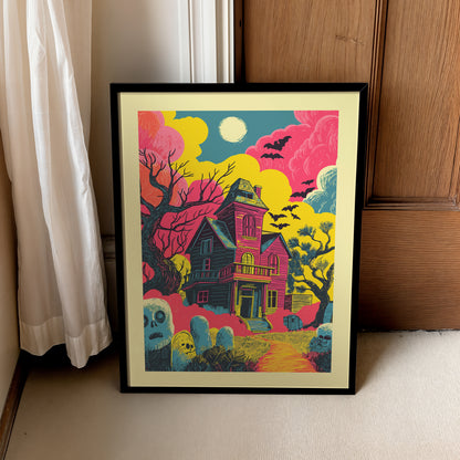 A framed art print featuring a colorful, stylized illustration of a haunted house, bats, and tombstones in pink, yellow, teal, and black, leaning against a wooden door next to a white curtain.