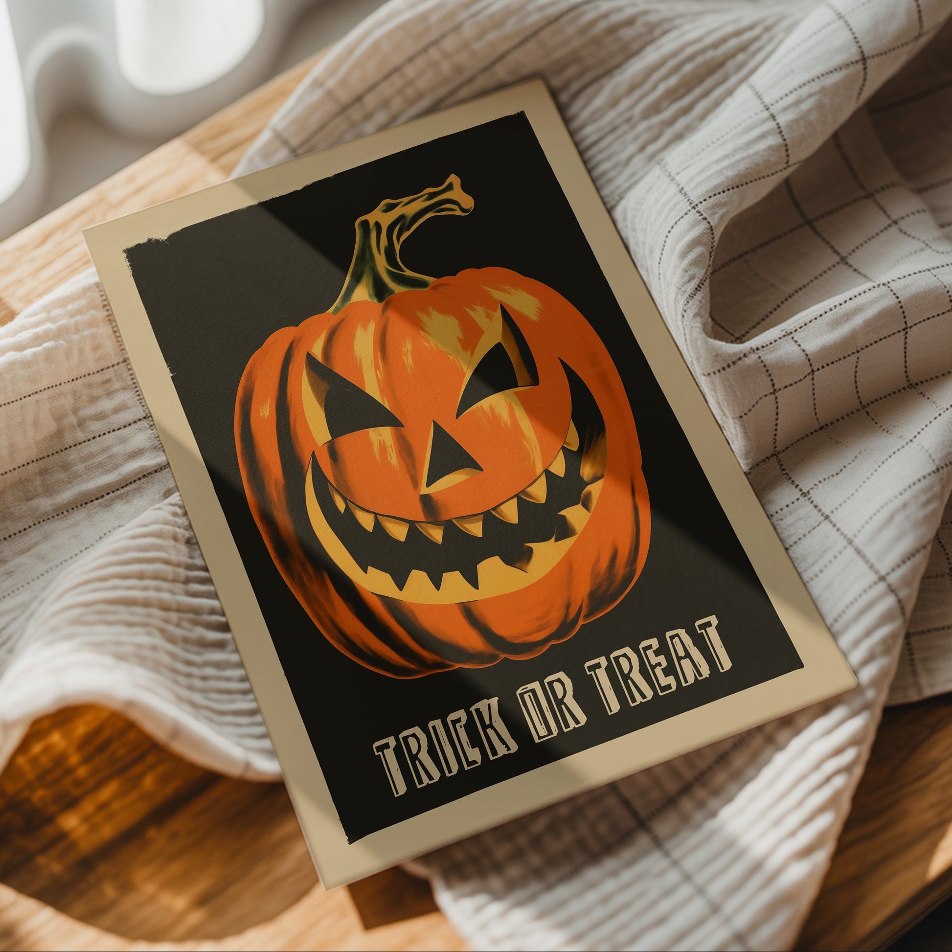 A Halloween greeting card featuring a carved orange pumpkin on a black background with the words 'TRICK OR TREAT' at the bottom, styled on a checkered cloth over a wooden surface.