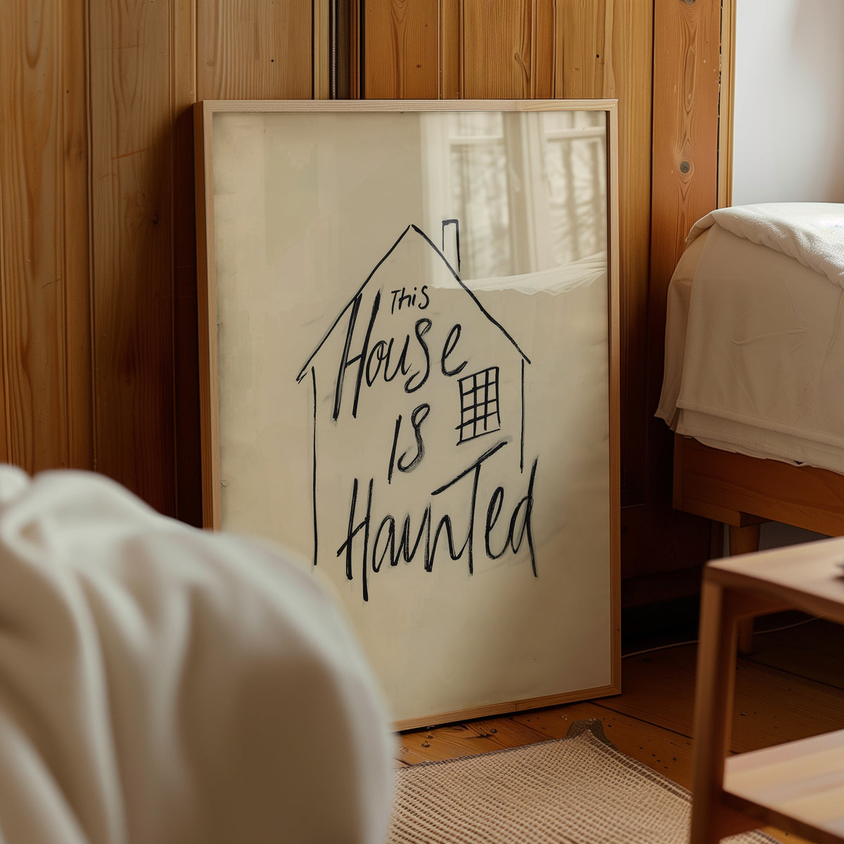 Minimalist haunted house quote poster with a hand-drawn house outline and “This House Is Haunted” lettering in black on a warm cream background.
