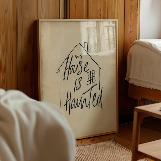 Minimalist haunted house quote poster with a hand-drawn house outline and “This House Is Haunted” lettering in black on a warm cream background.