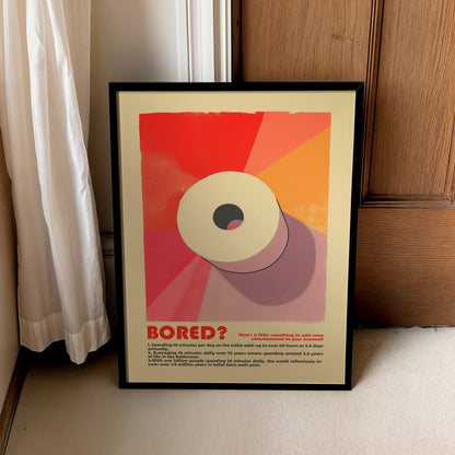 “Bored?” bathroom poster in a black frame leaning beside a curtain and wooden cabinet.