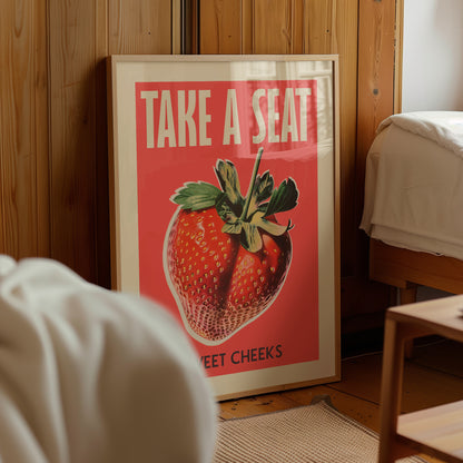 “Take a Seat Sweet Cheeks” toilet poster displayed beside a bed in a warm bedroom.